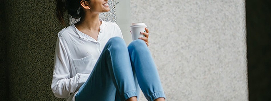 mujer sentada en una ventana con un café