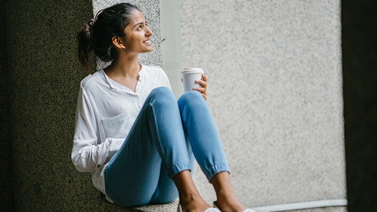 mujer sentada en una ventana con un café