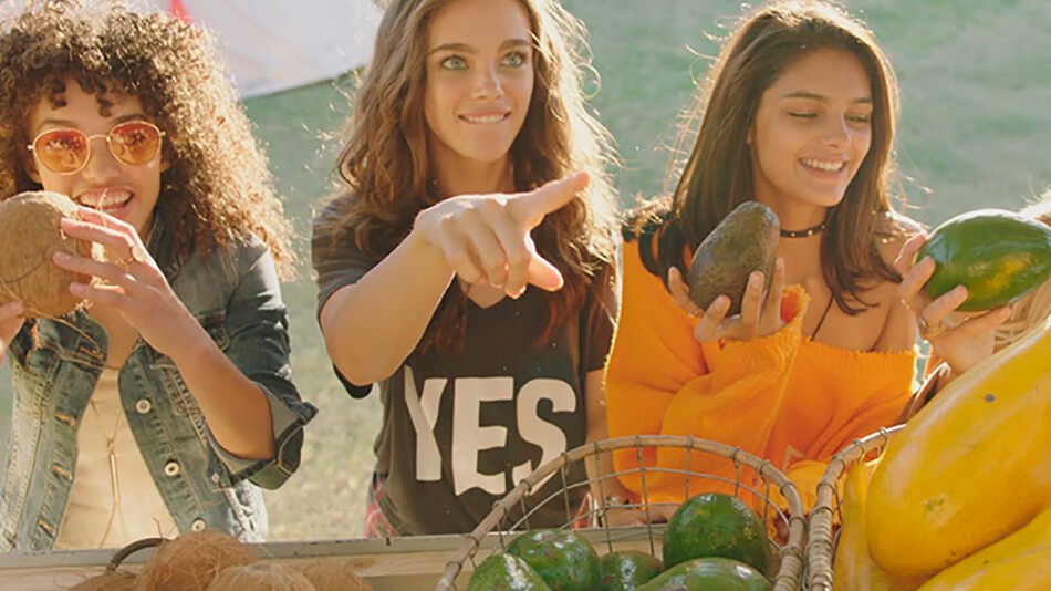 tres mujeres jóvenes comprando fruta en un mercado