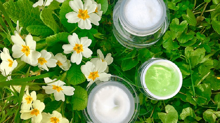 botes de crema sobre césped y flores