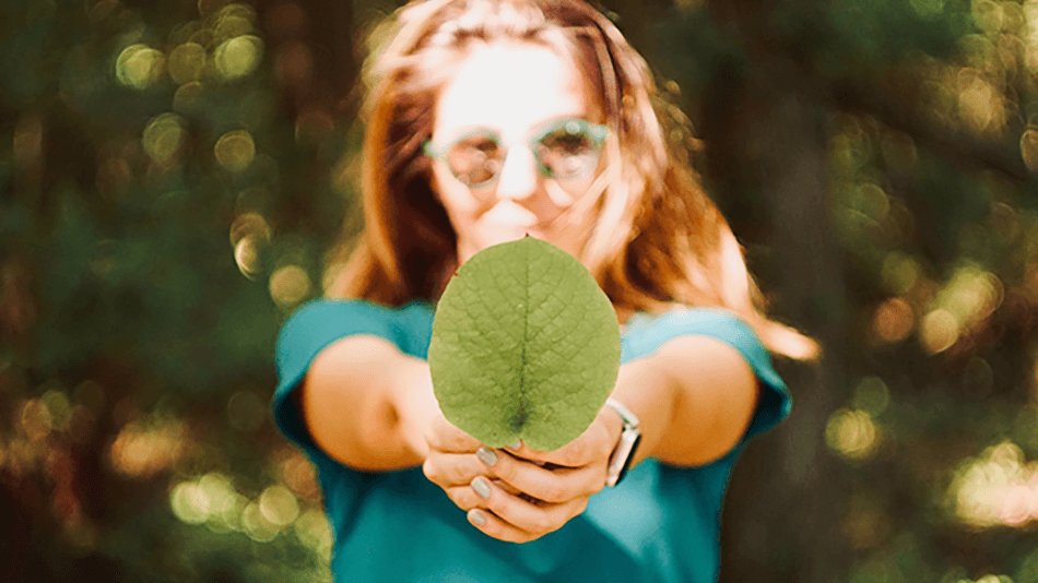Chica con gafas mostrando una hoja verde
