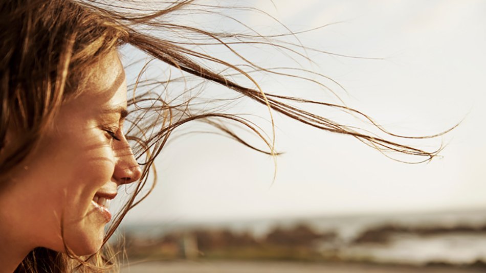 mujer con el pelo al viento y ojos cerrados