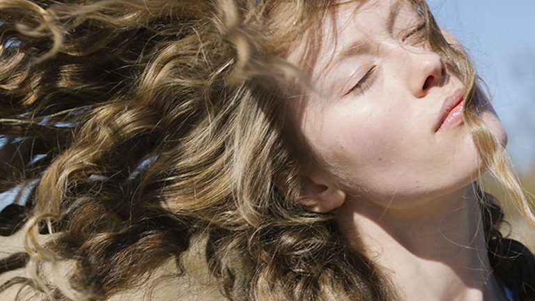 mujer rubia pelo rizado al viento