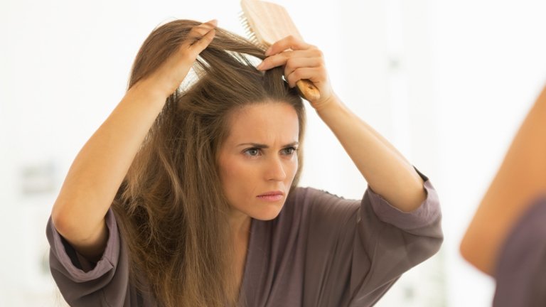 mujer frente al espejo tocándose el pelo con las manos