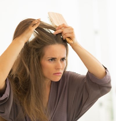 mujer frente al espejo tocándose el pelo con las manos
