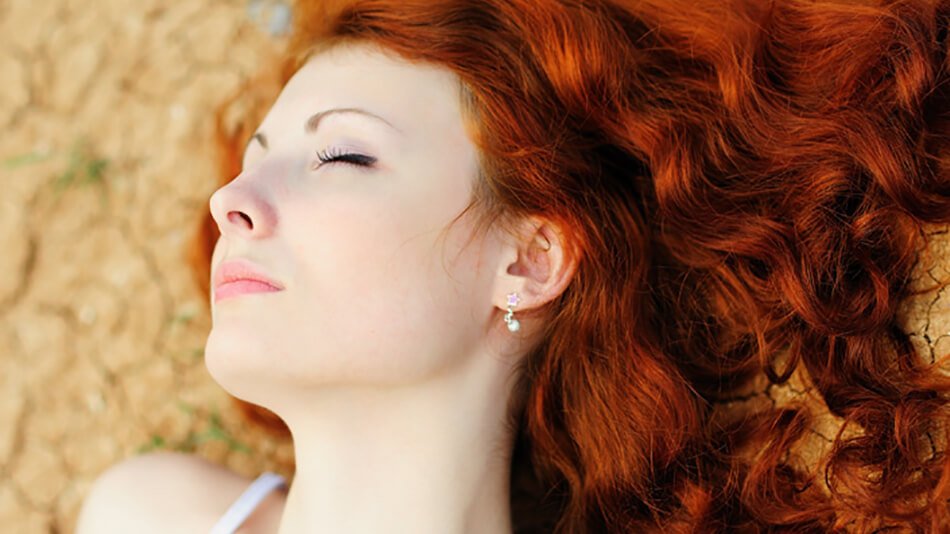 mujer pelirroja de pelo largo y ondulado tumbada