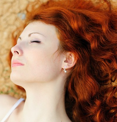 mujer pelirroja de pelo largo y ondulado tumbada