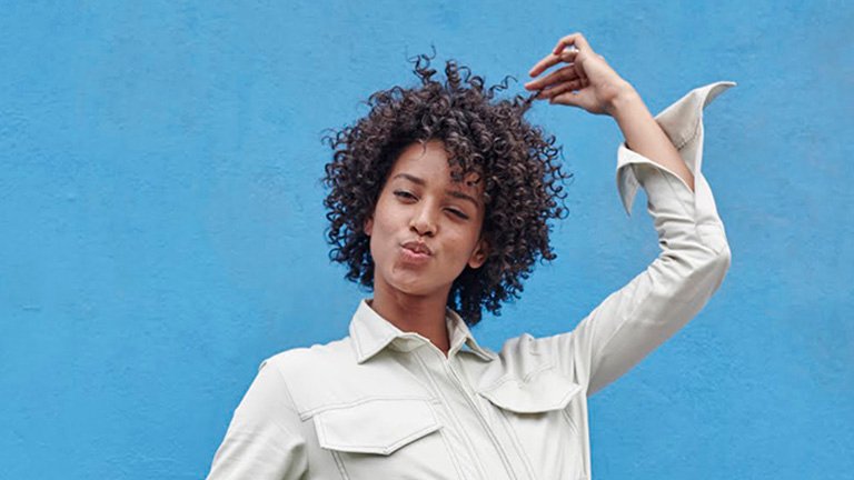 Chica cogiendose el pelo rizado con una mano