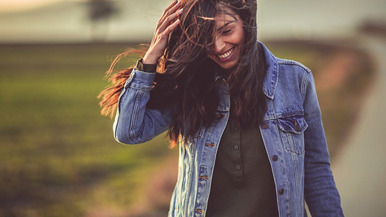 mujer morena pelo largo liso al viento en el campo