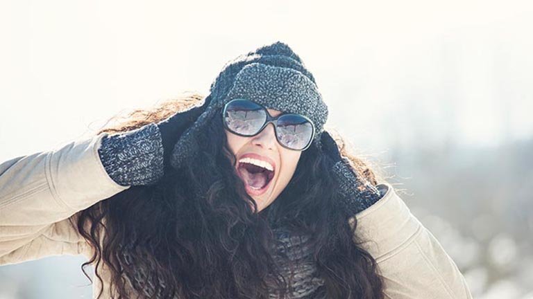 mujer pelo largo rizado con gorro de invierno y gafas de sol