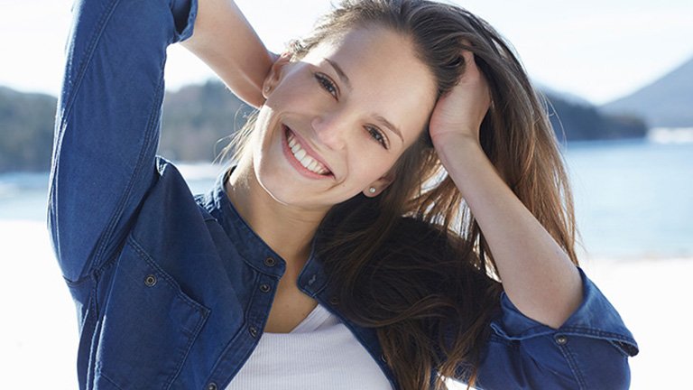 Mujer sonriendo tocándose el pelo