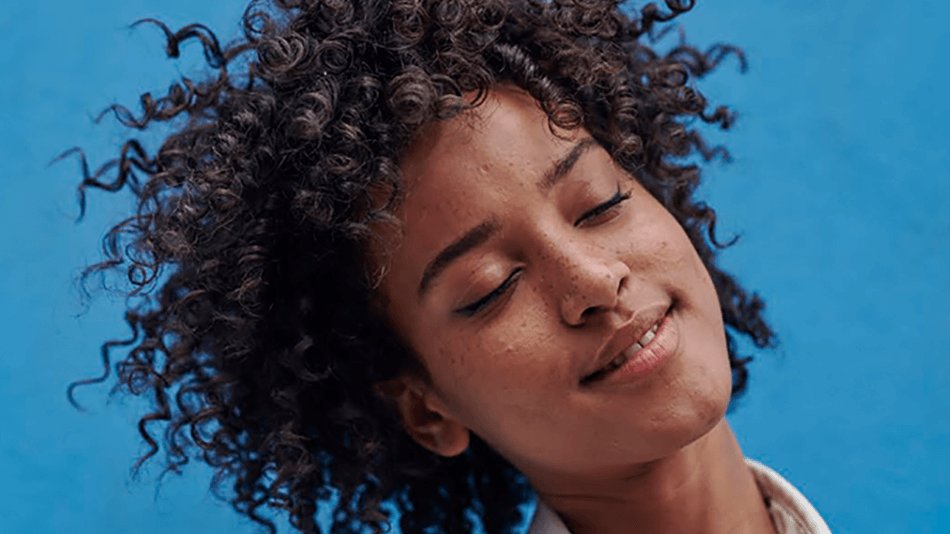 Chica con ojos cerrados con sonrisa y pelo rizado