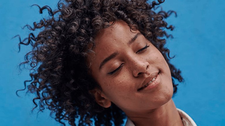 Chica con ojos cerrados con sonrisa y pelo rizado