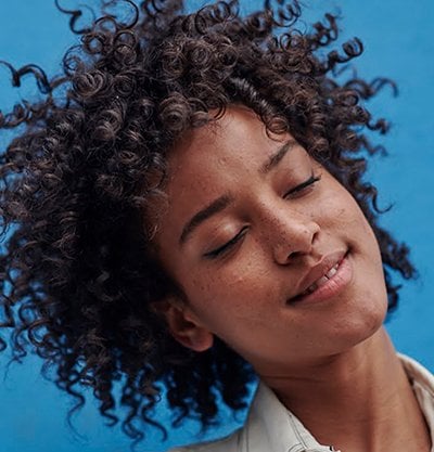 Chica con ojos cerrados con sonrisa y pelo rizado