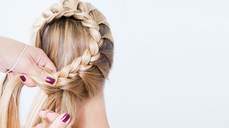 mujer pelo rubio largo haciéndose una trenza