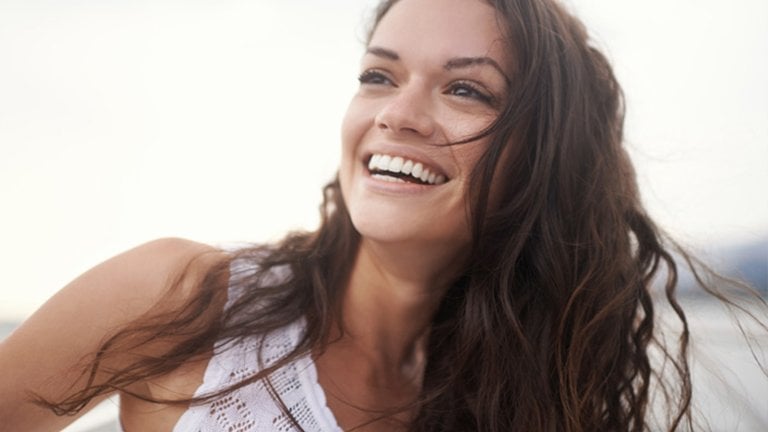 mujer morena de pelo largo rizado riéndose