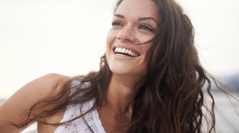 mujer morena de pelo largo rizado riéndose