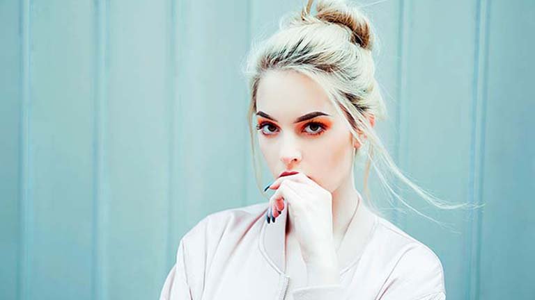 Chica rubia con recogido y mano en la boca