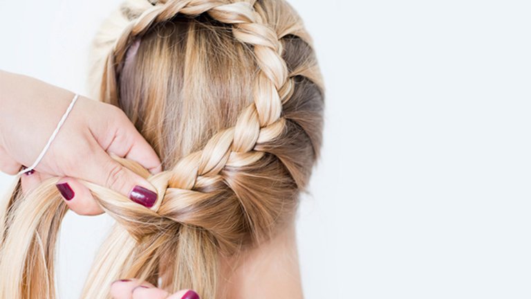 Mano recogiendo trenza sobre cabeza femenina