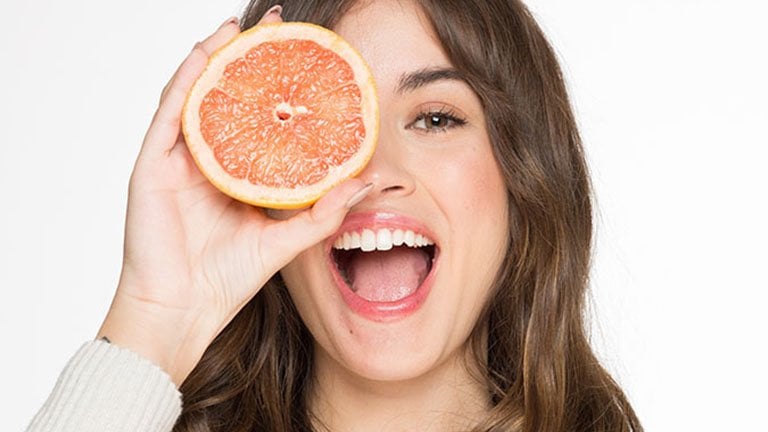 Mujer sonriente con fruta en el rostro