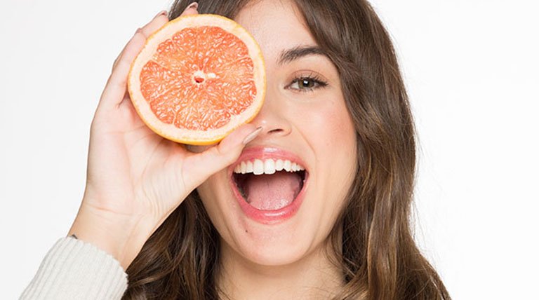 Mujer sonriente con fruta en el rostro