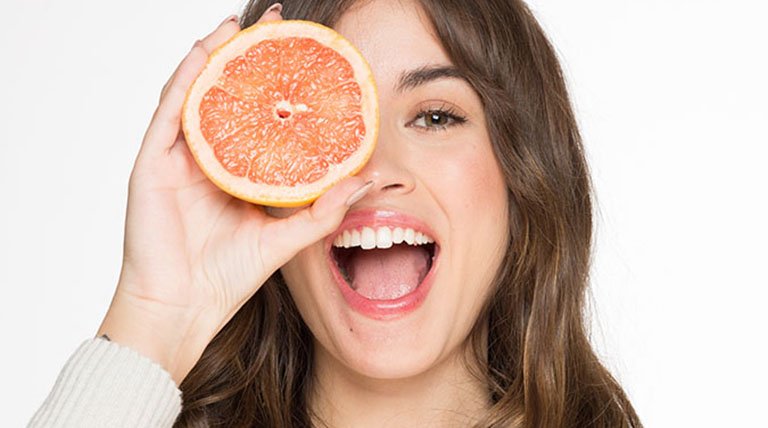 Mujer sonriente con fruta en el rostro