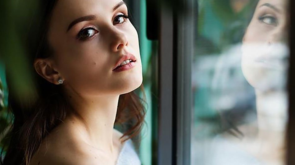 Rostro de mujer con reflejo en cristal