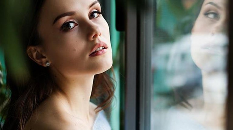 Rostro de mujer con reflejo en cristal