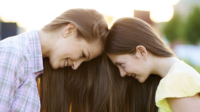 Madre e hija sonriendo enfrentando sus bonitos cabellos