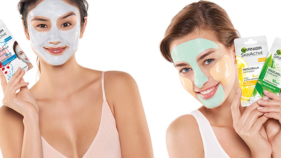 Dos mujeres con mascarilla facial enseñando productos de belleza