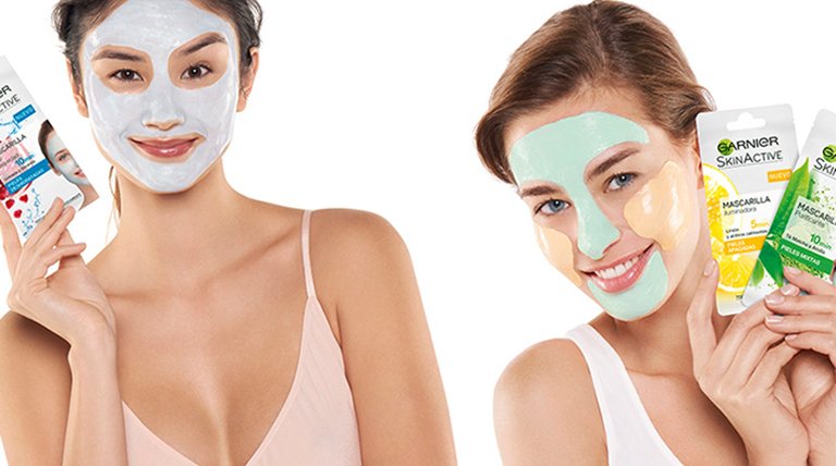 Dos mujeres con mascarilla facial enseñando productos de belleza