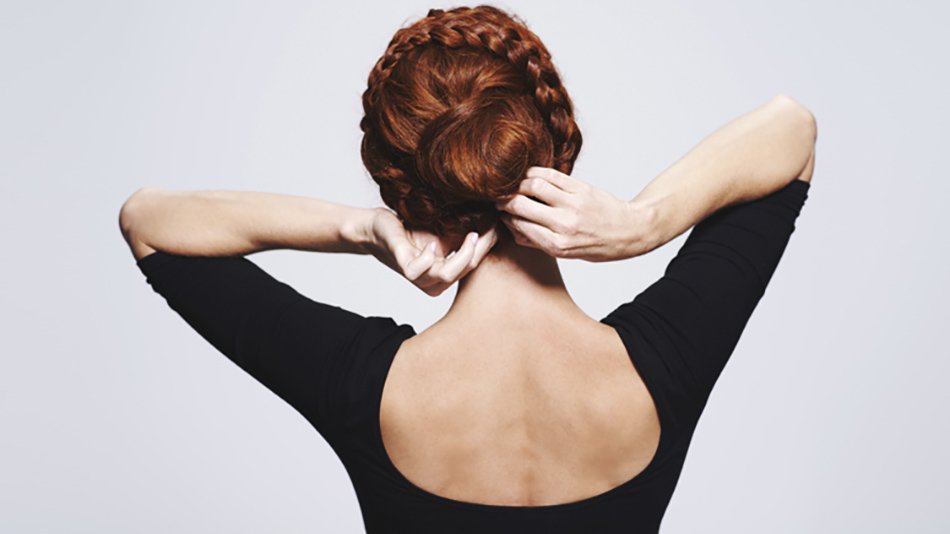 Mujer de espaldas arreglándose trenza en forma de moño