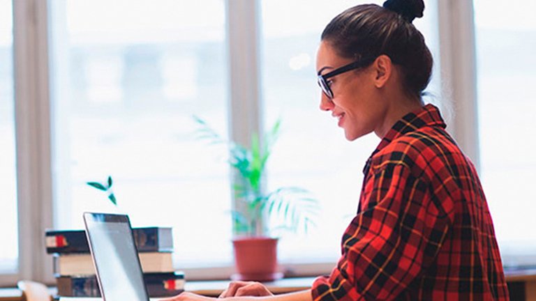 Mujer con moño y gafas trabajando con un ordenador