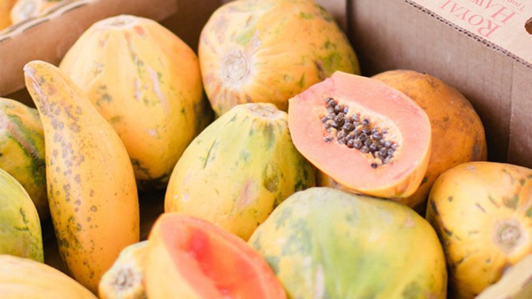 Caja con papayas, alguna partidas en dos