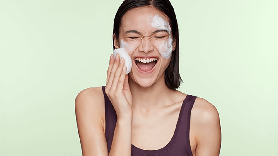 Mujer frotándose con esponja el rostro