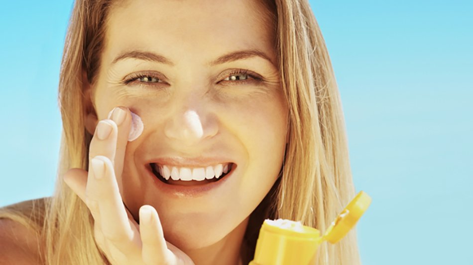 Mujer sonriente poniéndose crema en el rostro