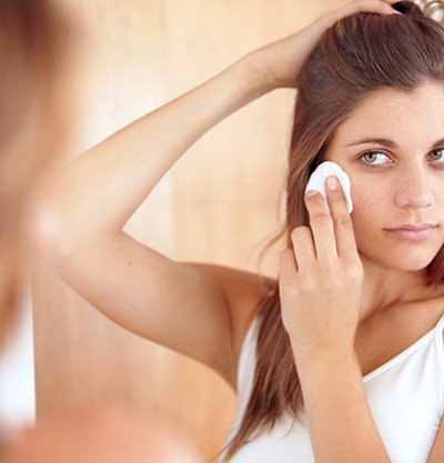 Mujer desmaquillándose frente a espejo
