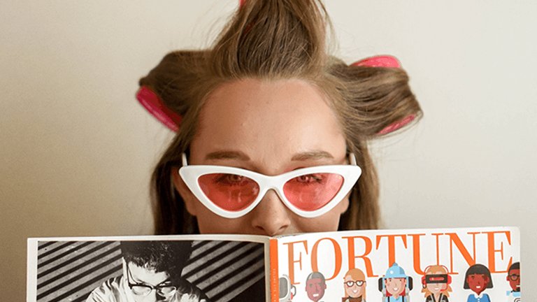 Mujer con gafas y rulos leyendo revista