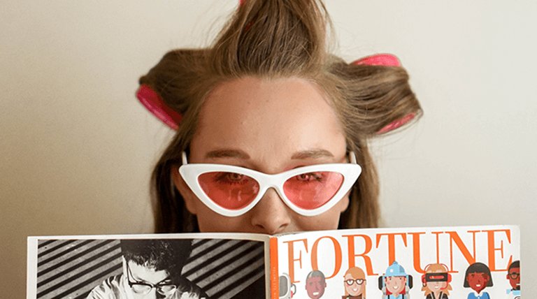 Mujer con gafas y rulos leyendo revista