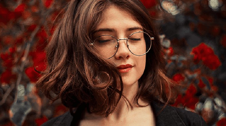 Mujer joven con gafas redondas y larga melena ondulada