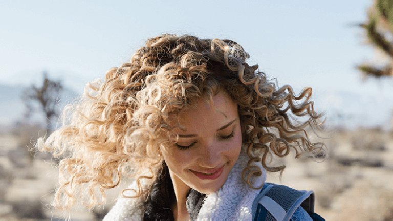 Mujer joven con pelo castaño claro rizado 