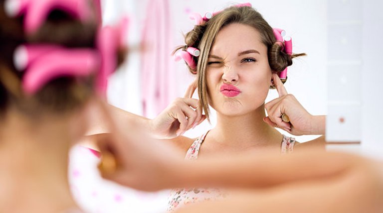 Mujer joven haciéndose un peinado divertido frente al espejo