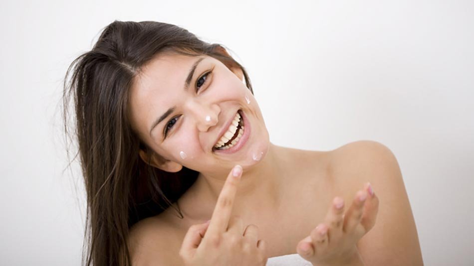 Chica poniendose crema en la cara con un dedo