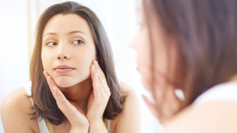 mujer morena mirándose la cara al espejo