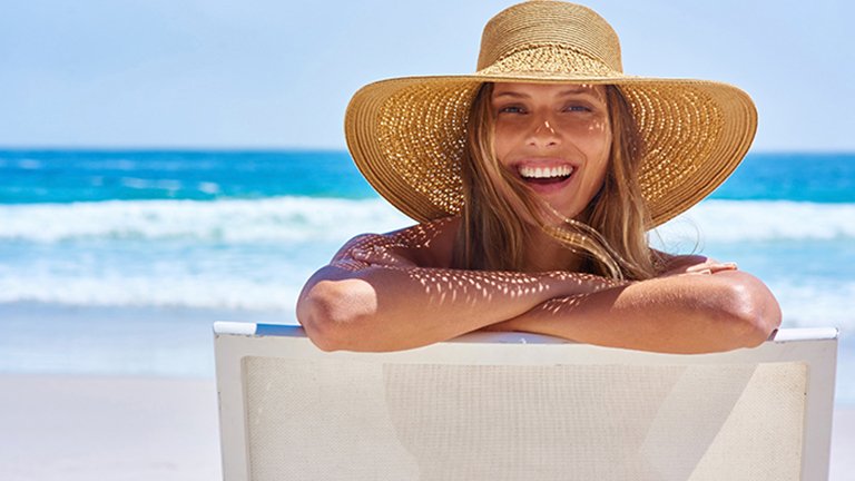 mujer en la playa con sombrero de paja