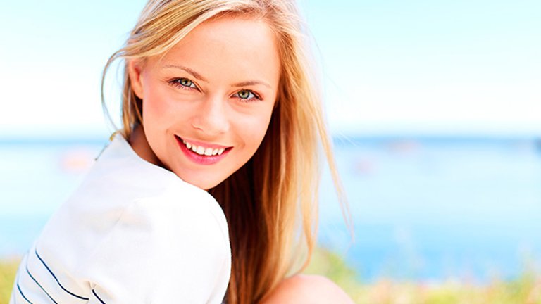 mujer sonriendo con mar de fondo