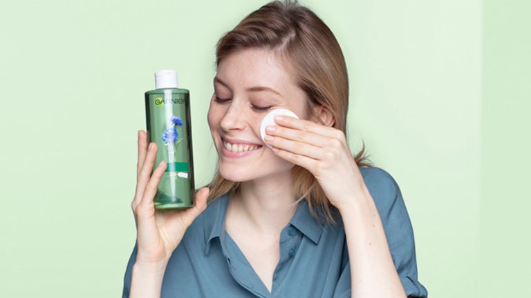 Chica limpiando su rostro con disco de algodon 