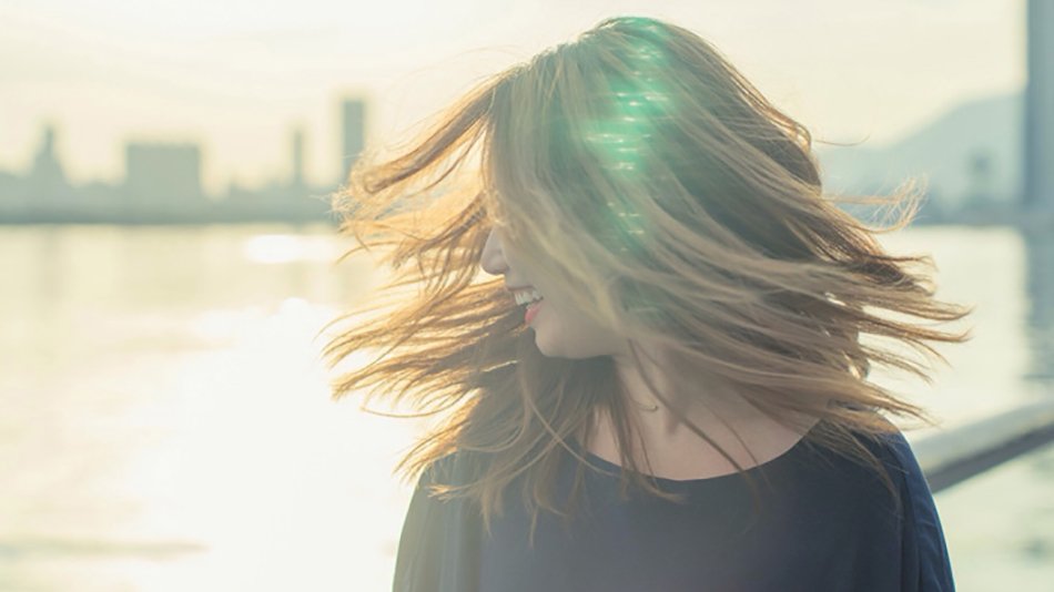 mujer pelo liso al viento con la ciudad de fondo