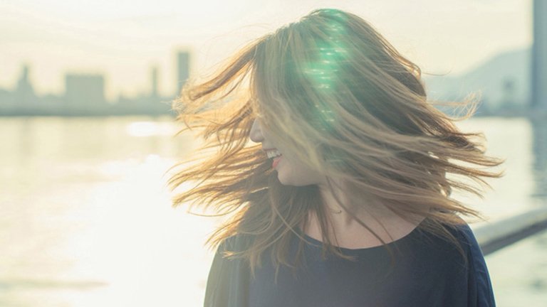 mujer pelo liso al viento con la ciudad de fondo