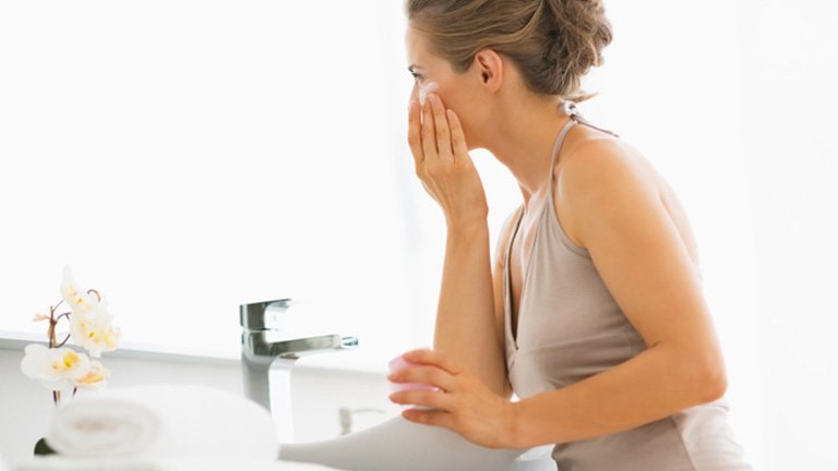 mujer echándose crema en la cara